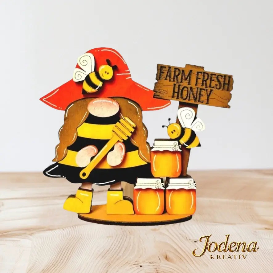 Bienenwichtelin_mit_Honigglaesern_auf_Holztisch