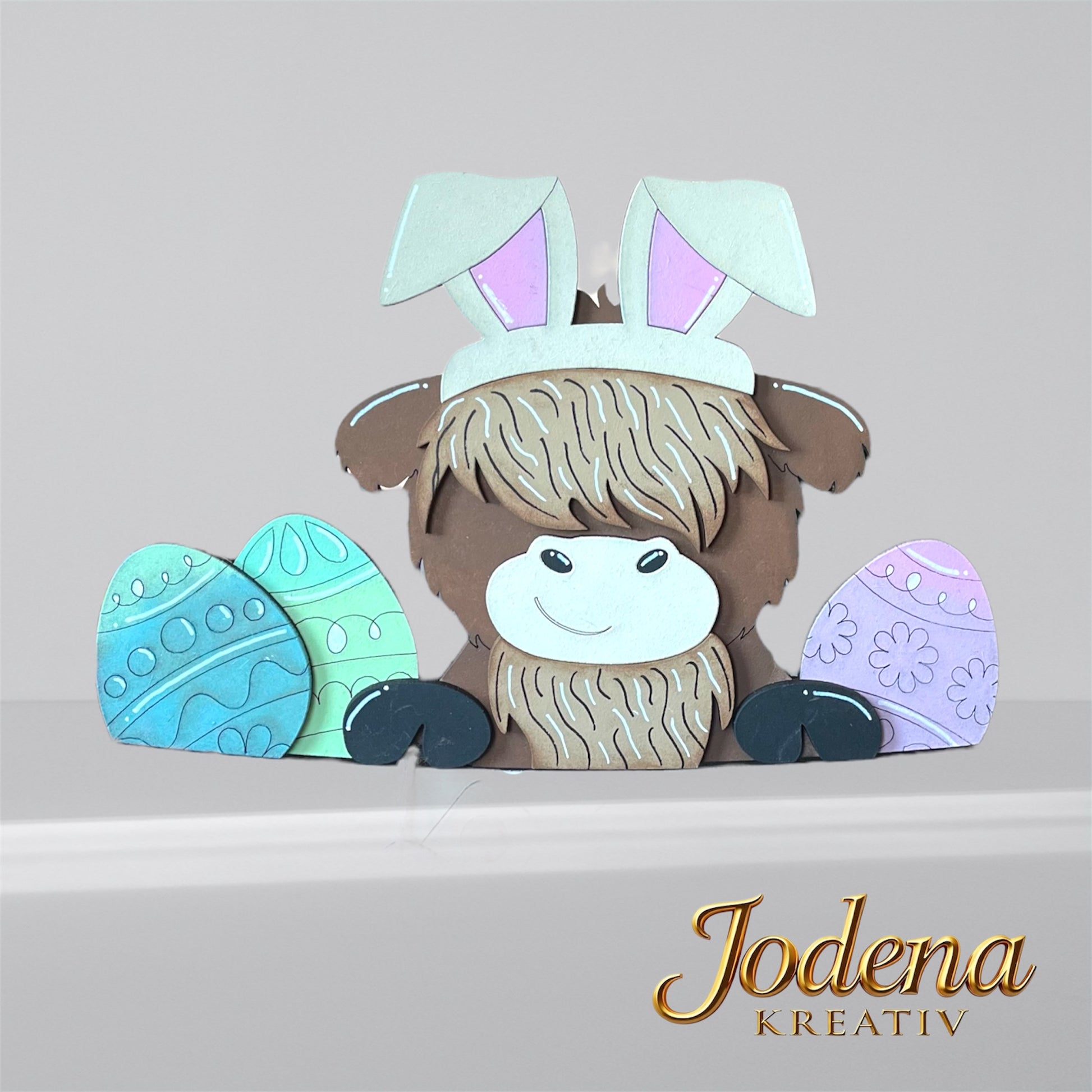 Austauschbarer Korbeinsatz mit Hochlandkuh und Hasenohren, sitzend neben bunten Ostereiern, einzeln